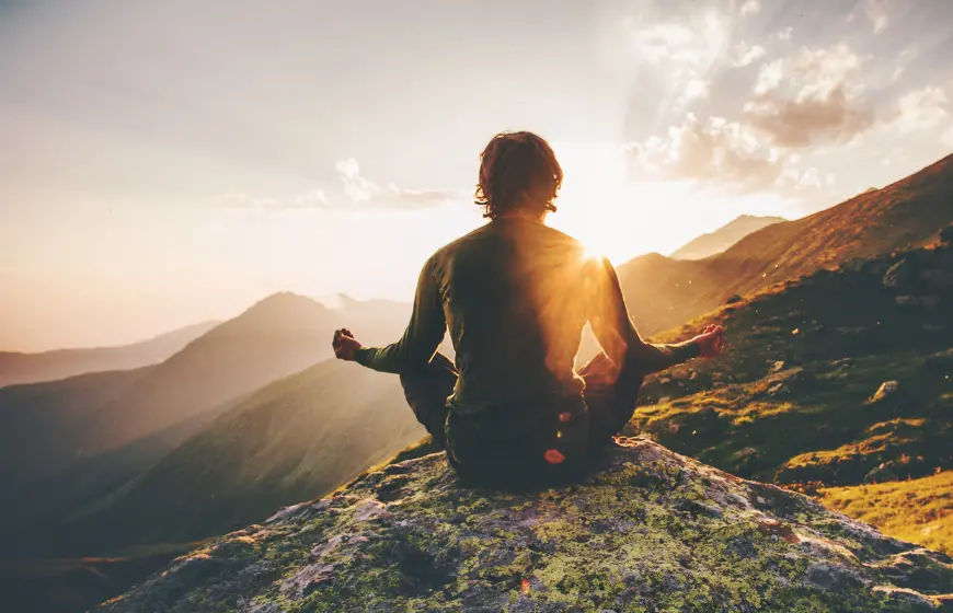 Mężczyzna na szczycie góry medytujący, aby zwalczyć stres i pokonać bruksizm.