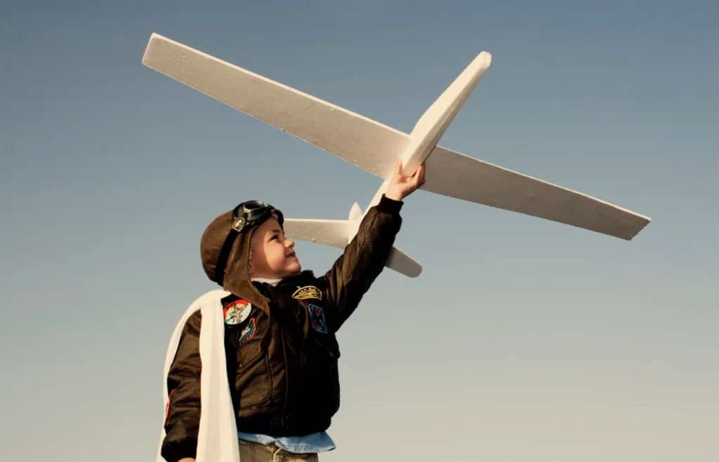 dziecko trzymające w ręce model samolotu i ubrane jak pilot z lat dziewiedździesiątych