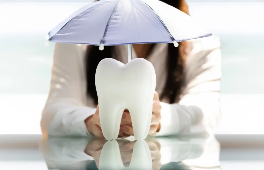 model zęba pod fioletowym parasolem jako symbol zapobiegania zjawisku, który potocznie określany jest jako dziura w zębie