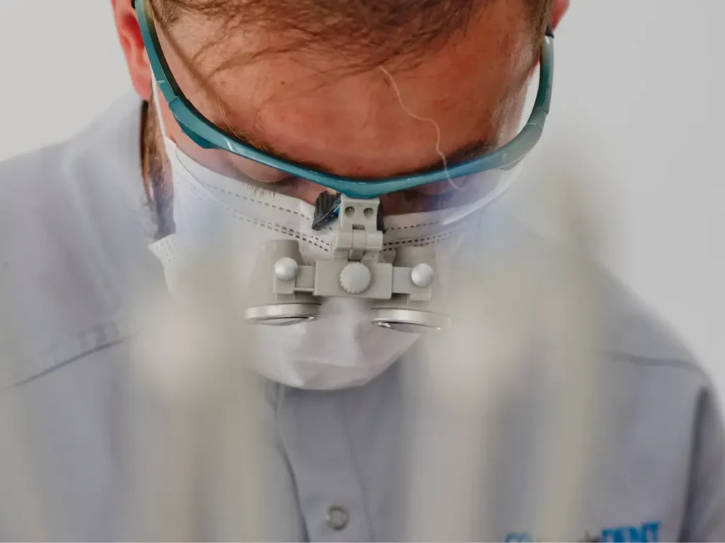 Dentysta Wojciech Skocz z PrecisDENT Centrum Implantologii i Stomatologii Mikroskopowej w lupach stomatologicznych podczas badania – precyzyjna diagnostyka i numeracja zębów.